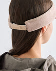Person wearing a beige headband with a brand logo on a light gray background