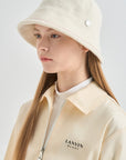 Person wearing a cream-colored hat and jacket with 'LANVIN BLANC' branding on a light gray background
