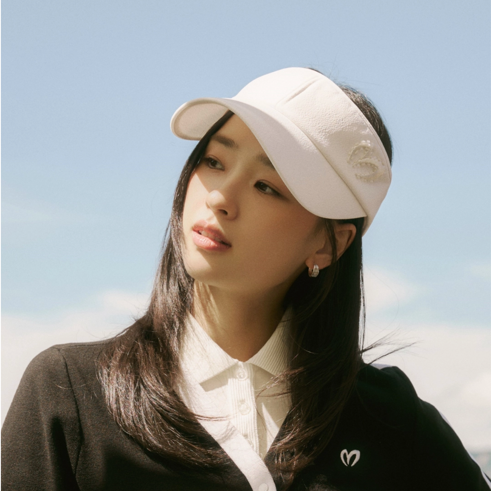 Woman wearing a white visor against a clear blue sky