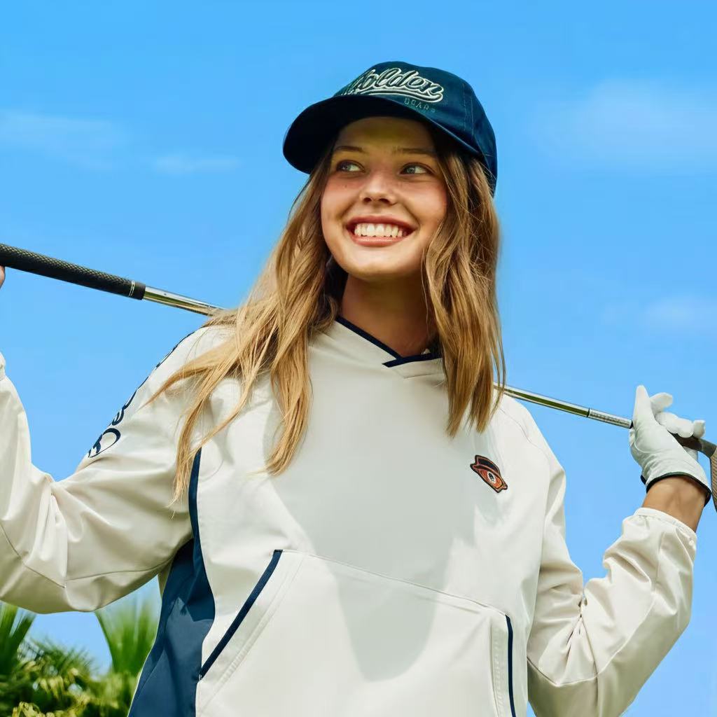 A girl wearing a navy hat and white hoodie.