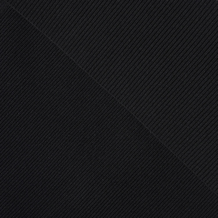 A close-up of a black ribbed fabric texture with diagonal ribbing and a diagonal seam running from top left to bottom right.