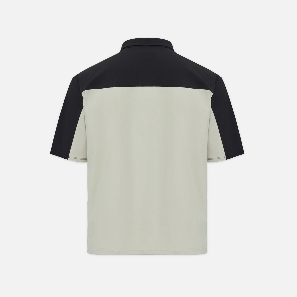 A short-sleeve polo shirt shown from the back, featuring a solid black yoke and sleeves with a light beige lower body, set against a plain light gray background.