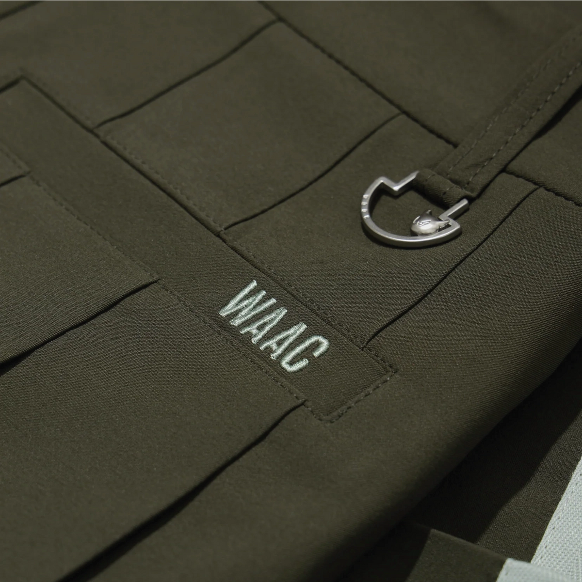 Close-up of khaki pleated skort with WAAC logo and metal ring detail