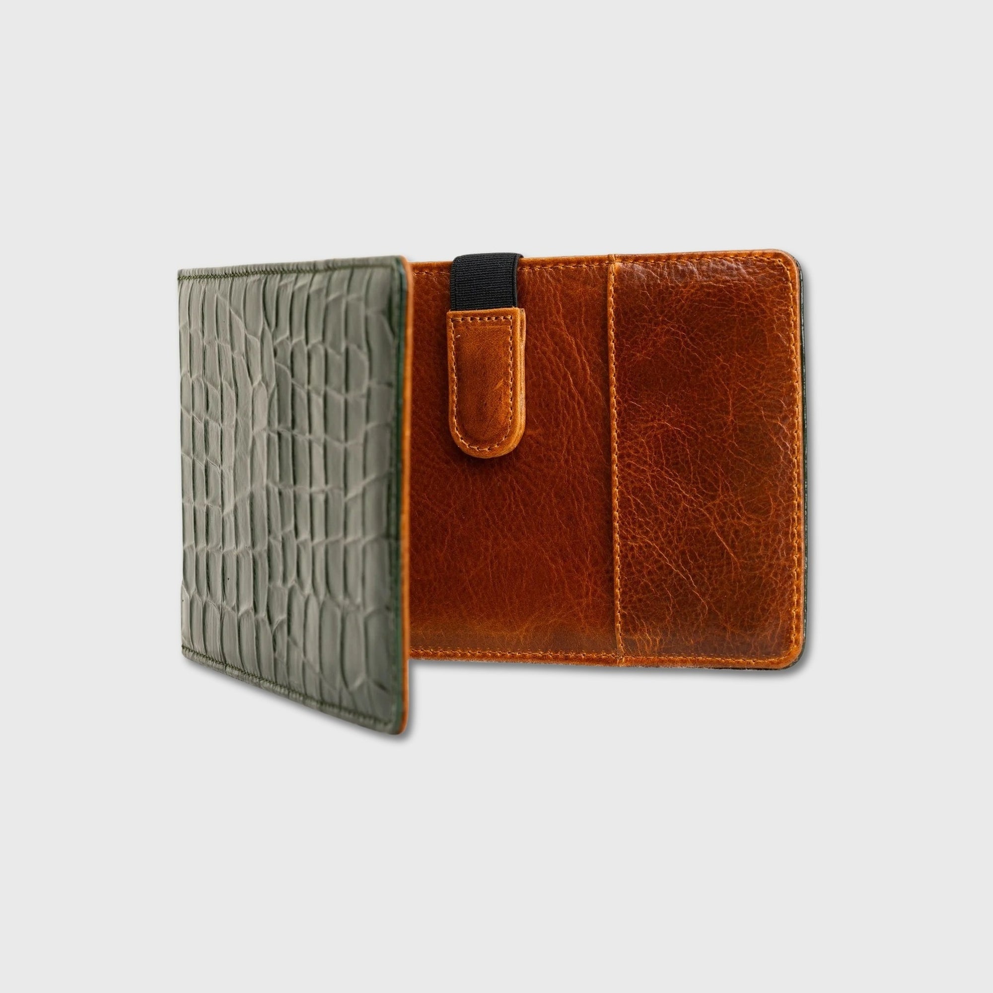 A two-tone leather  yardage book holder shown open against a light gray background. The left side features a textured olive green exterior with an alligator or crocodile pattern, while the right side reveals a warm brown interior with card slots and a matching leather tab closure with a black elastic band.