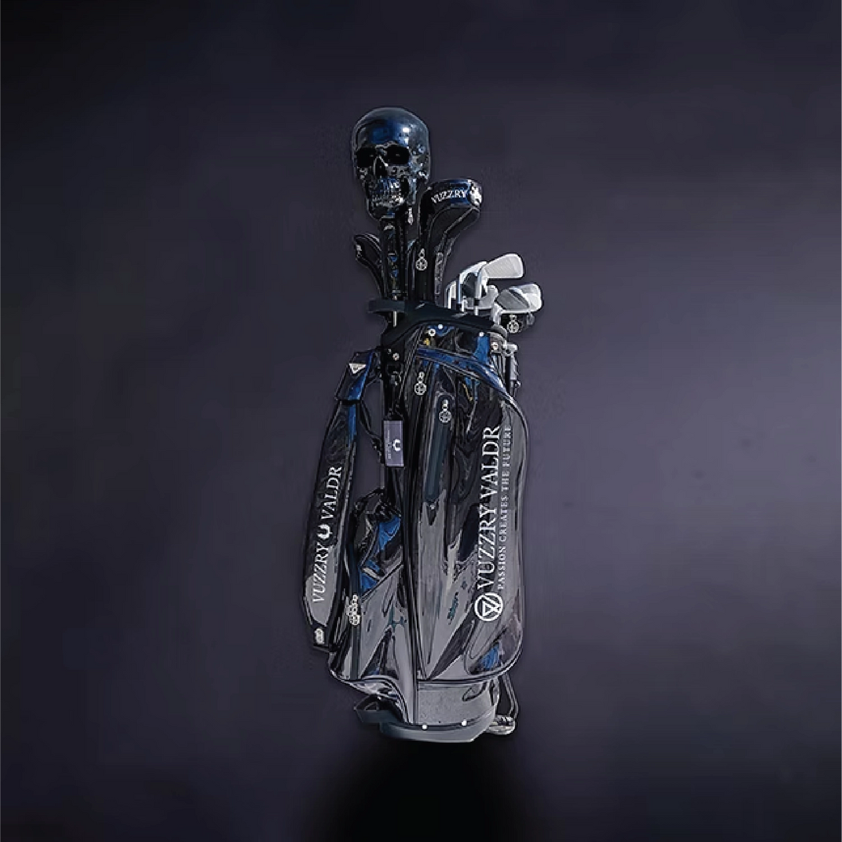 A metallic silver and black golf bag with blue accents, filled with golf clubs, set against a dark studio background. The bag features the brand name 'VUZZRY VALDR' printed vertically in white.