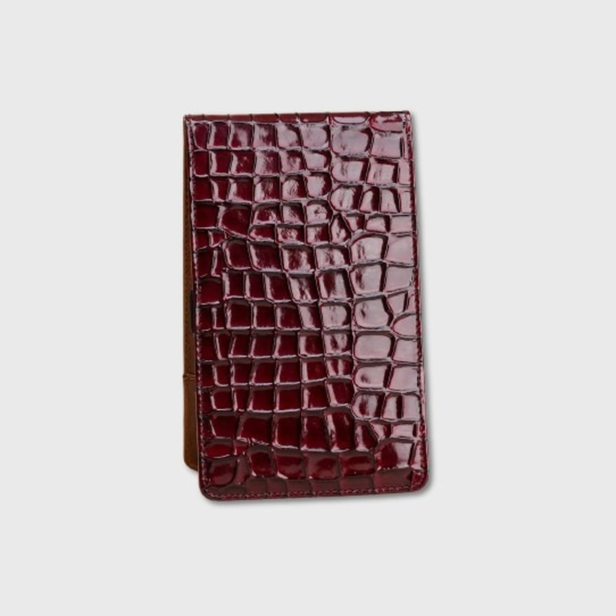 A yardage book holder made of glossy crocodile-embossed leather in a deep burgundy red, shown against a light gray background.
