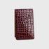 A yardage book holder made of glossy crocodile-embossed leather in a deep burgundy red, shown against a light gray background.