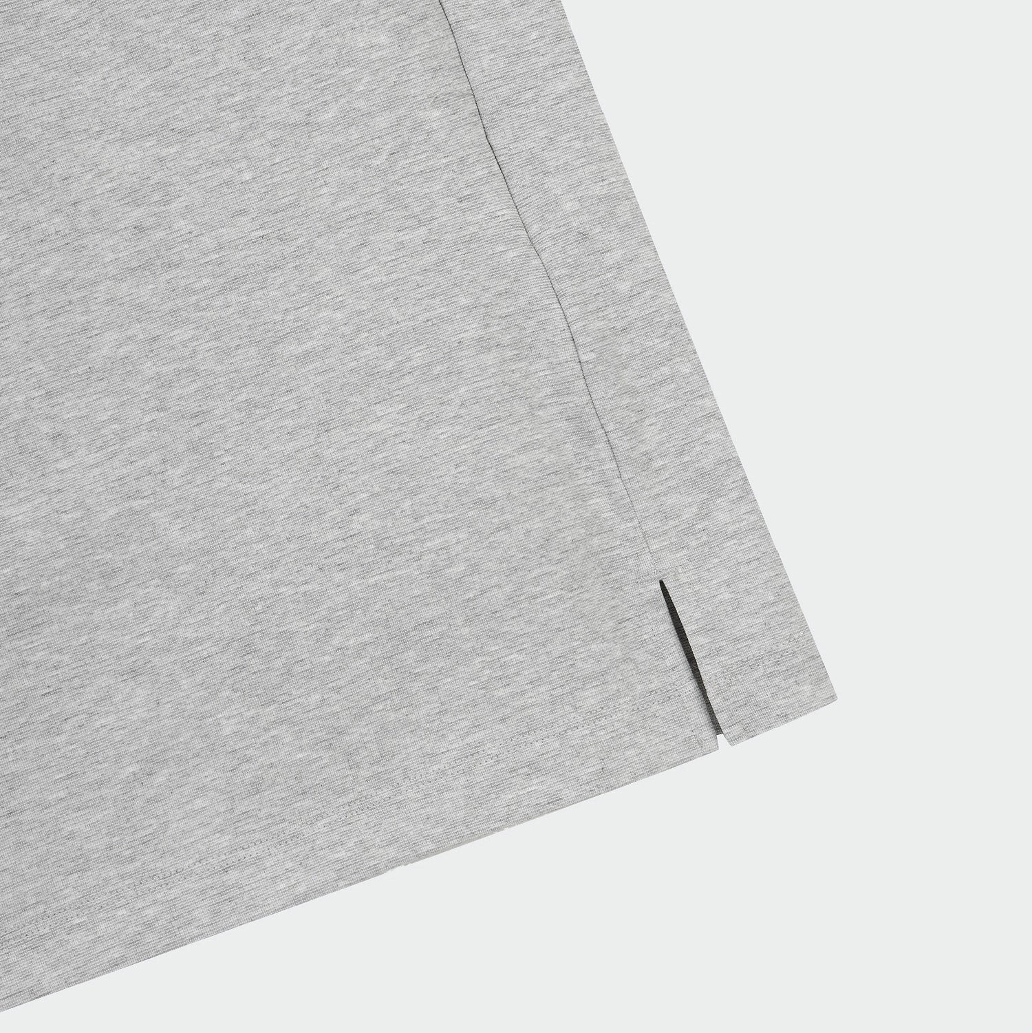 Close-up of a light gray heathered fabric corner with a visible seam and small slit detail, set against a plain light gray background.