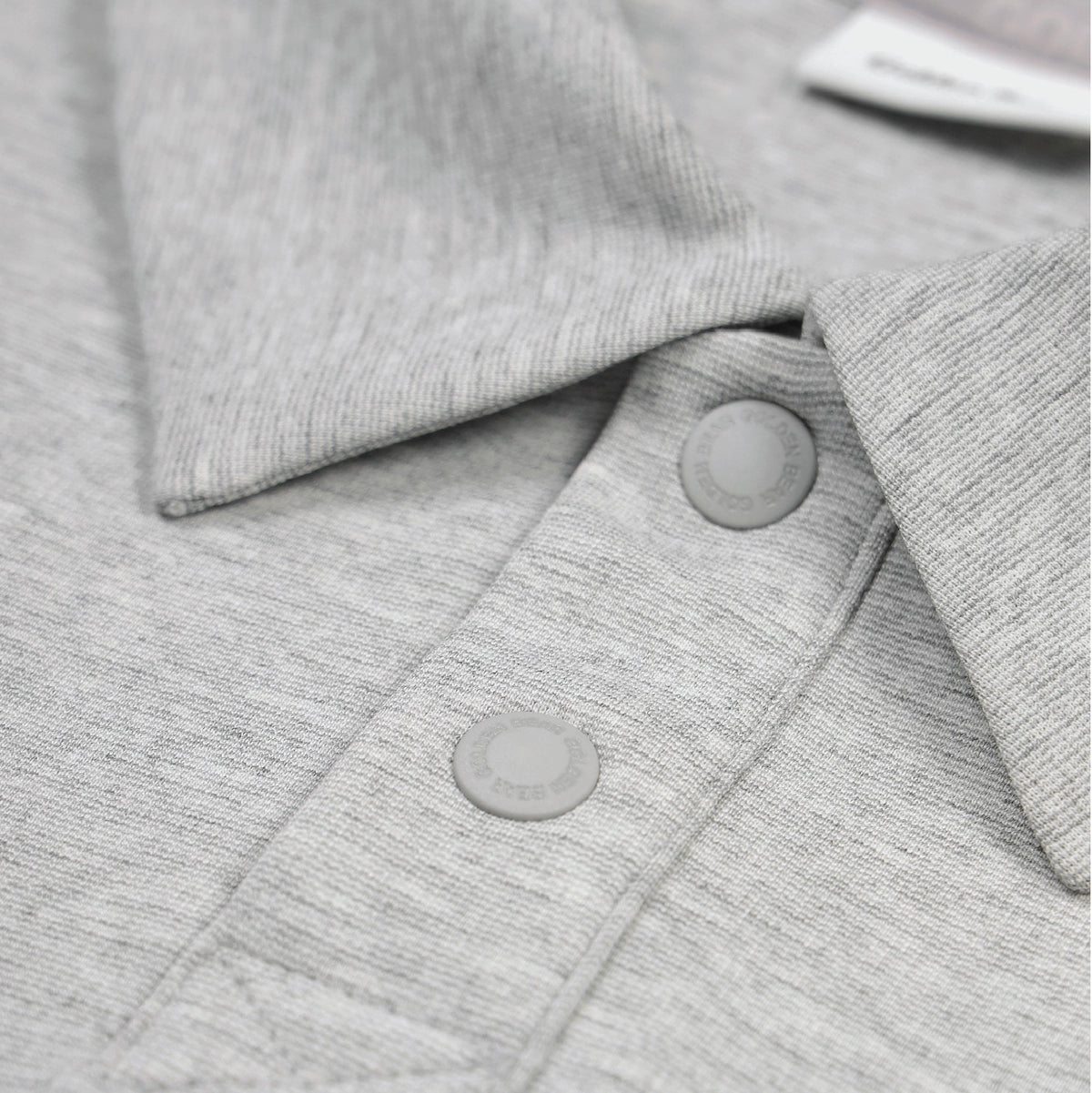 Close-up of a light gray heathered knit garment with a collar and two matching round snap buttons.