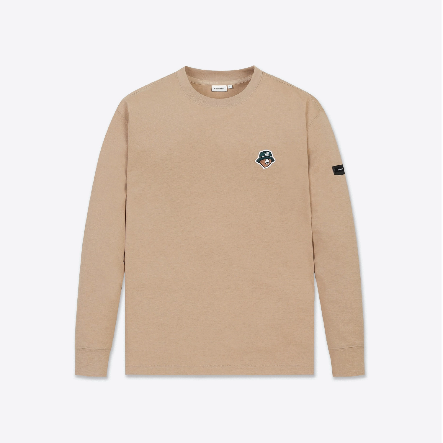 A beige long-sleeve crewneck shirt with a small embroidered patch on the left chest and a black brand patch on the right sleeve, shown against a light gray background.