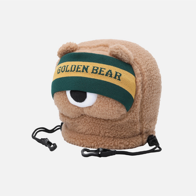 A plush teddy bear headwear piece in tan fleece with a green and yellow knit band across the forehead reading 'GOLDEN BEAR', plus a white eye patch and black drawstrings, shown on a light gray background.