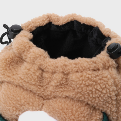 Close-up of a soft sherpa drawstring pouch in warm tan/beige with a black interior lining and black drawstring hardware.