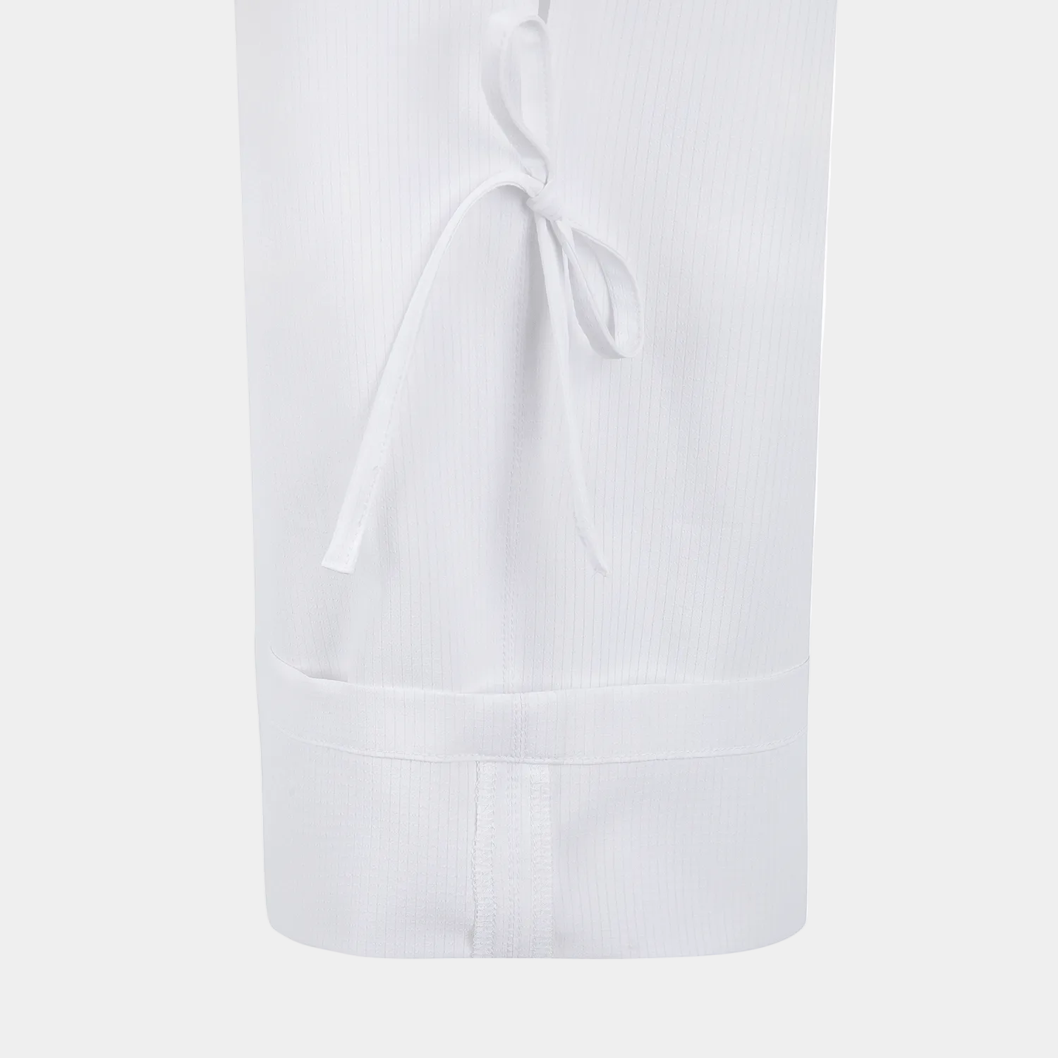 Close-up of a white ribbed fabric garment, likely a skirt or long dress section, with a tie detail near the top and a gathered waistband at the bottom, shown on a plain white background.