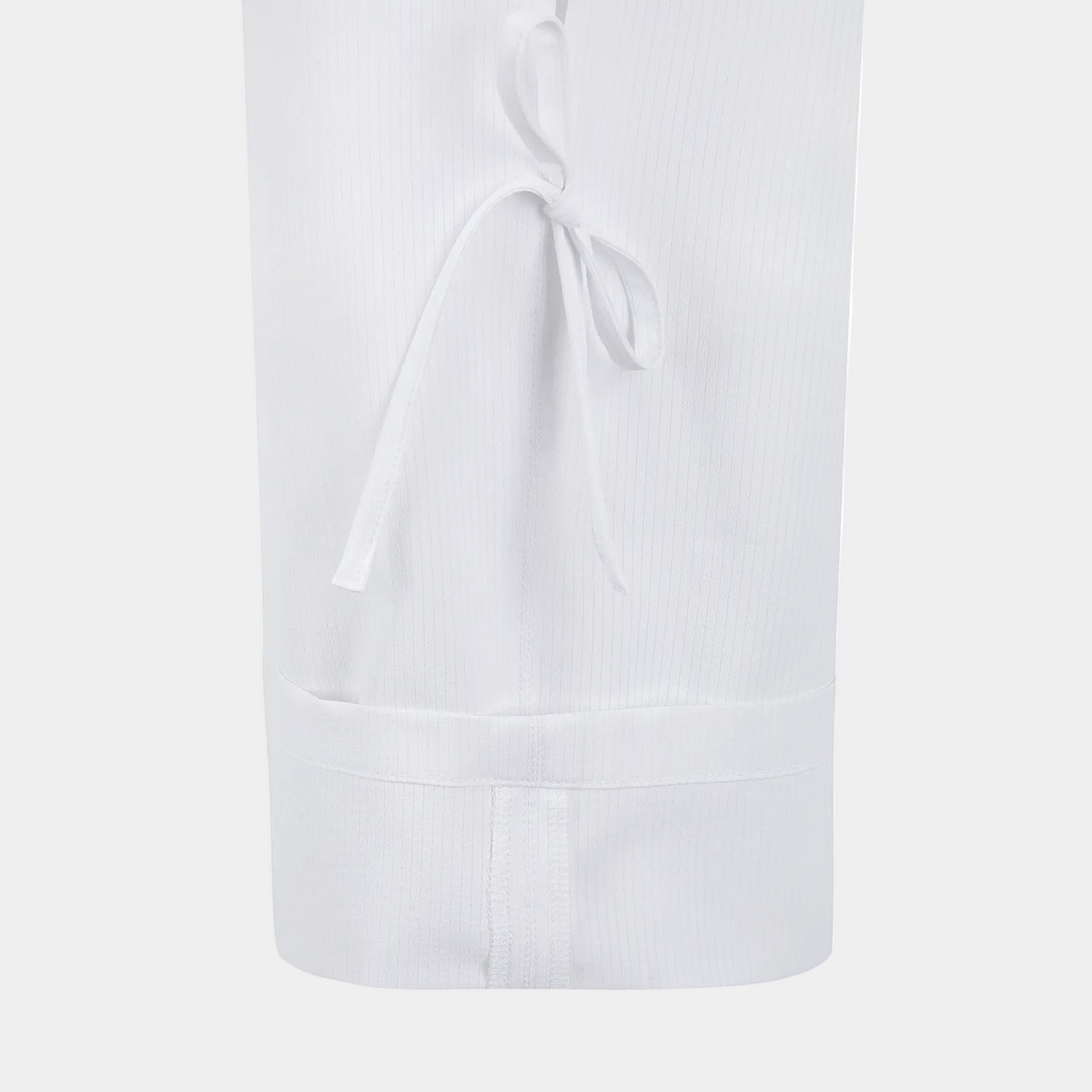 Close-up of a white ribbed fabric garment, likely a skirt or long dress section, with a tie detail near the top and a gathered waistband at the bottom, shown on a plain white background.