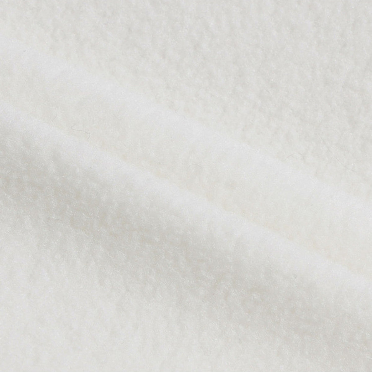 A close-up of soft white plush fabric with a textured, fleece-like surface and gentle folds.