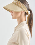Woman wearing a beige visor and matching shirt on a white background