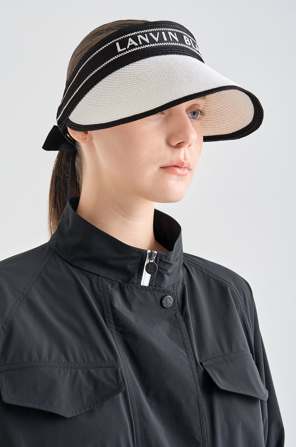 Woman wearing a black and white visor with 'LANVIN' branding on a light gray background