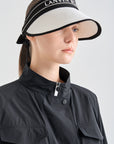 Woman wearing a black and white visor with 'LANVIN' branding on a light gray background