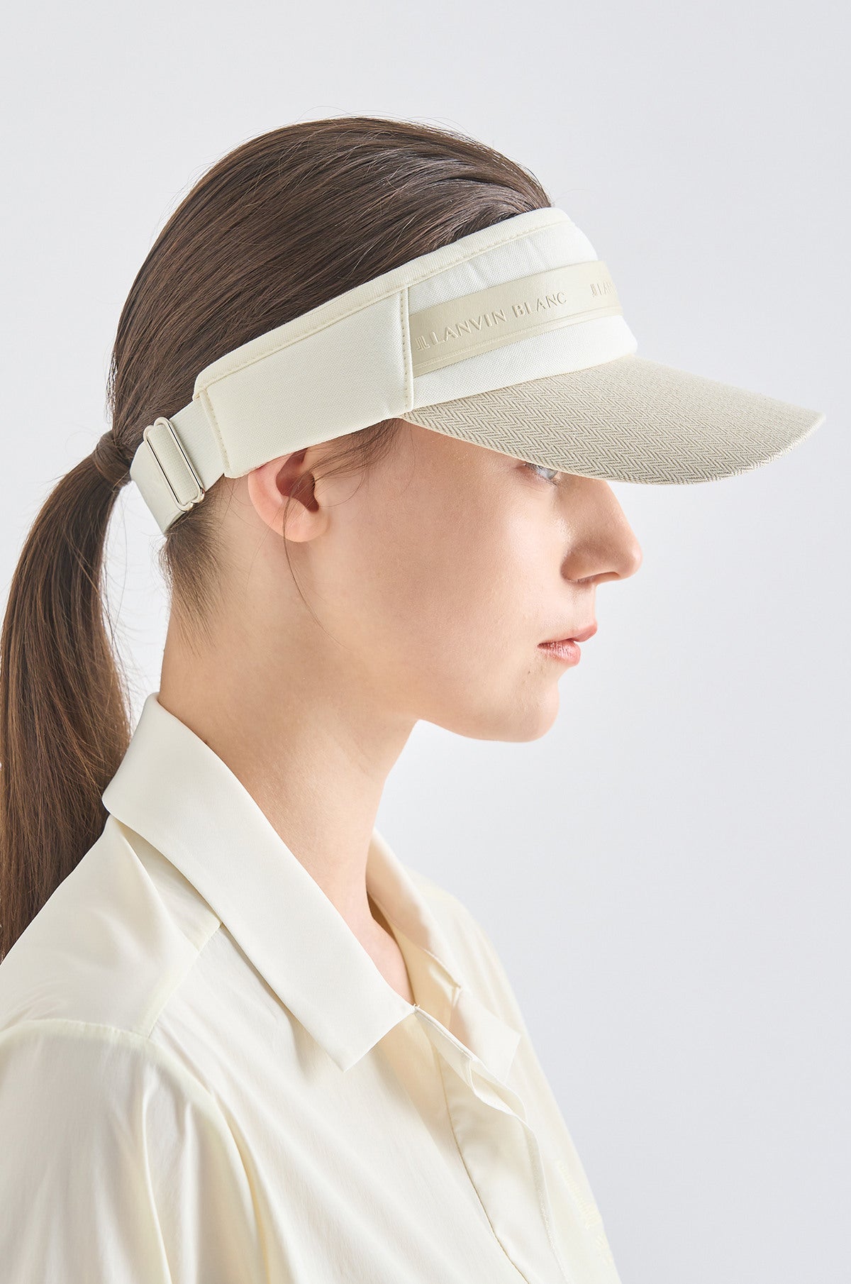 Woman wearing a beige visor against a light gray background