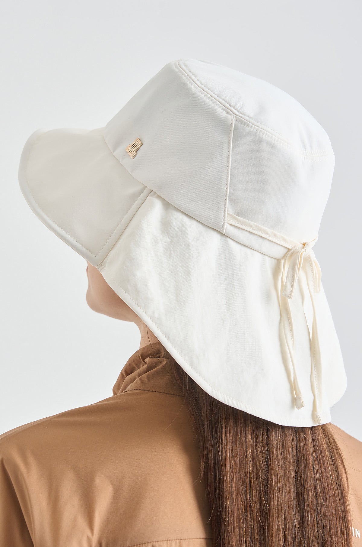 White sun hat worn by a person on a light gray background