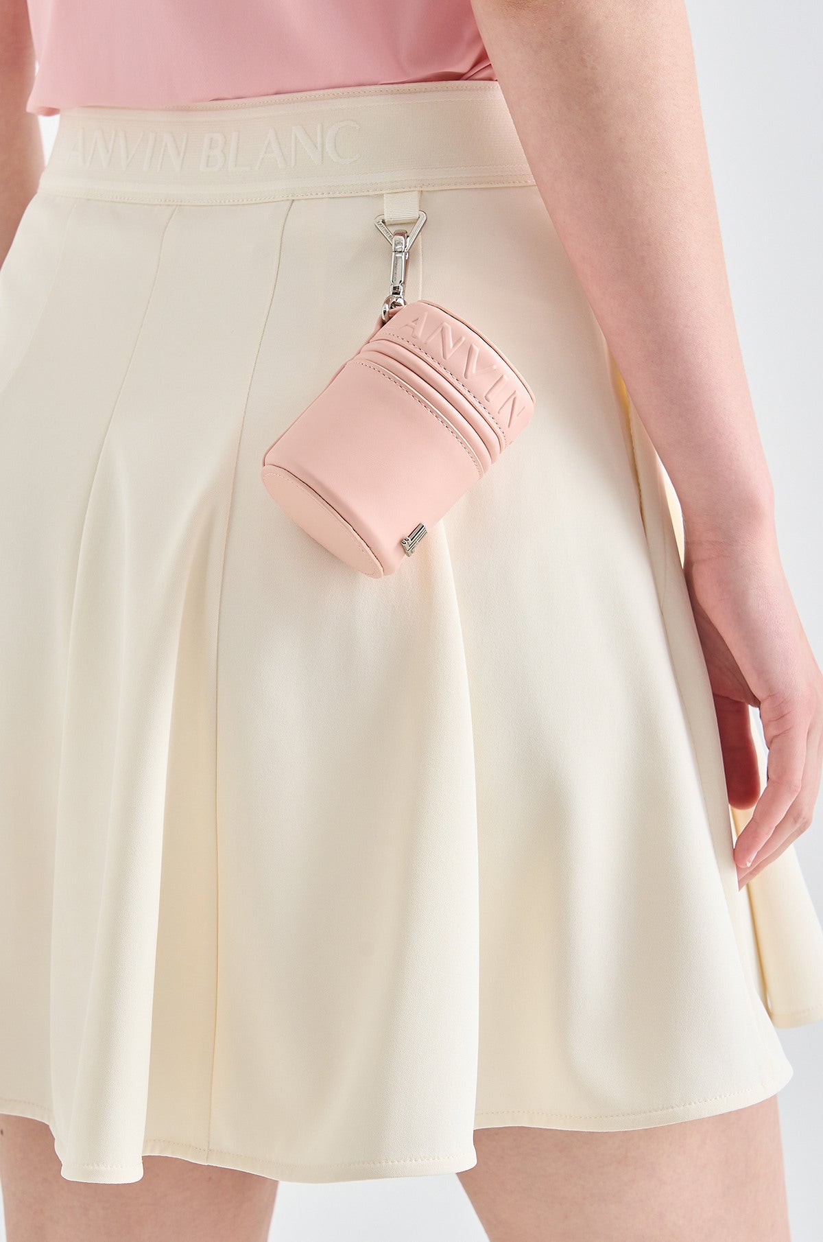 Person wearing a light pink top and white skirt with a matching pink pouch.