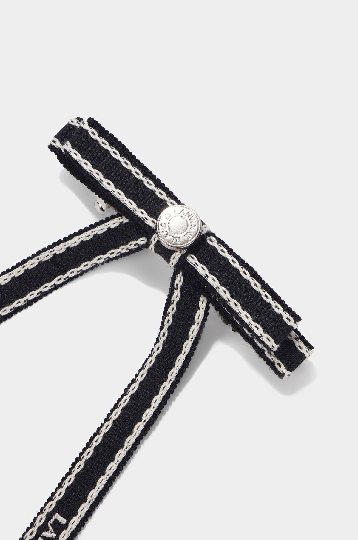 Black ribbon with silver chain and decorative button on a white background