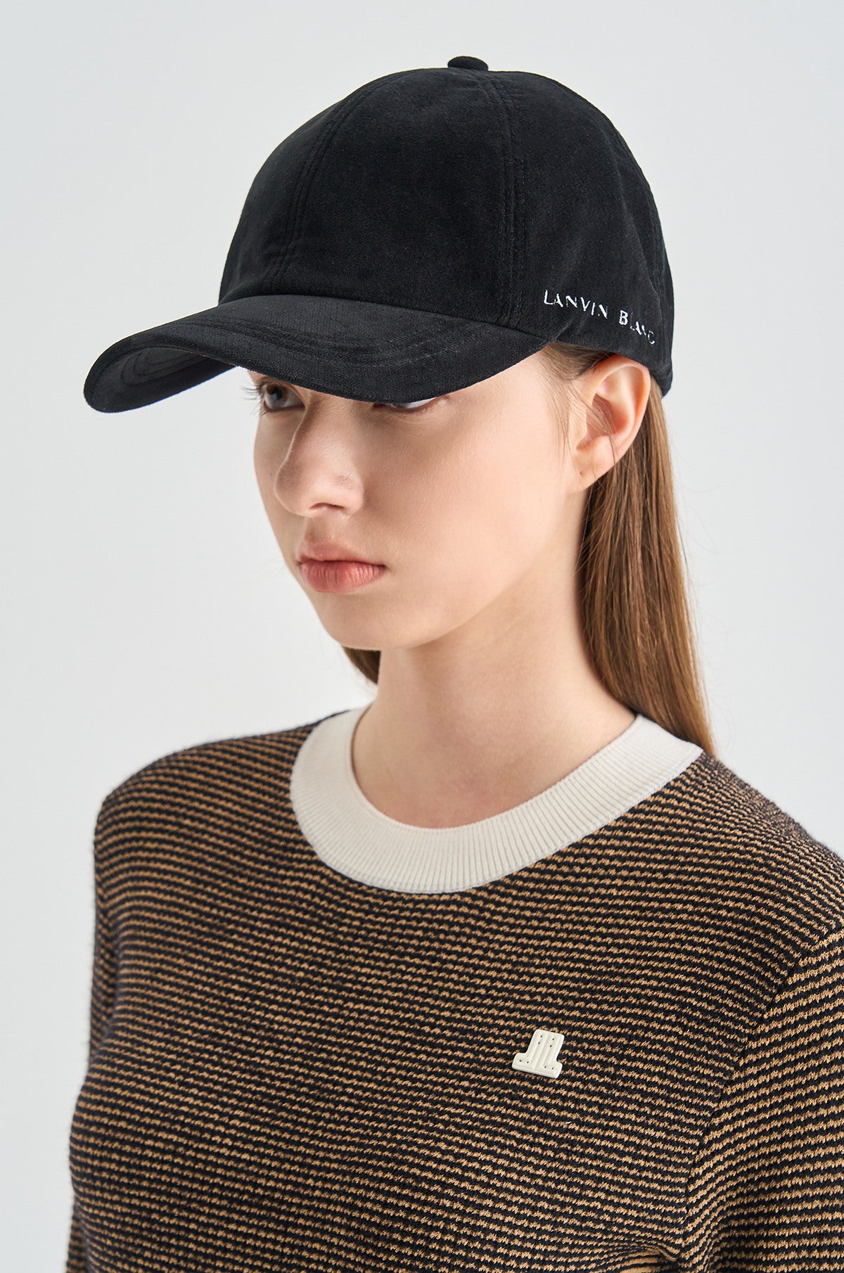 Person wearing a black cap with 'LANVIN' branding on a light gray background