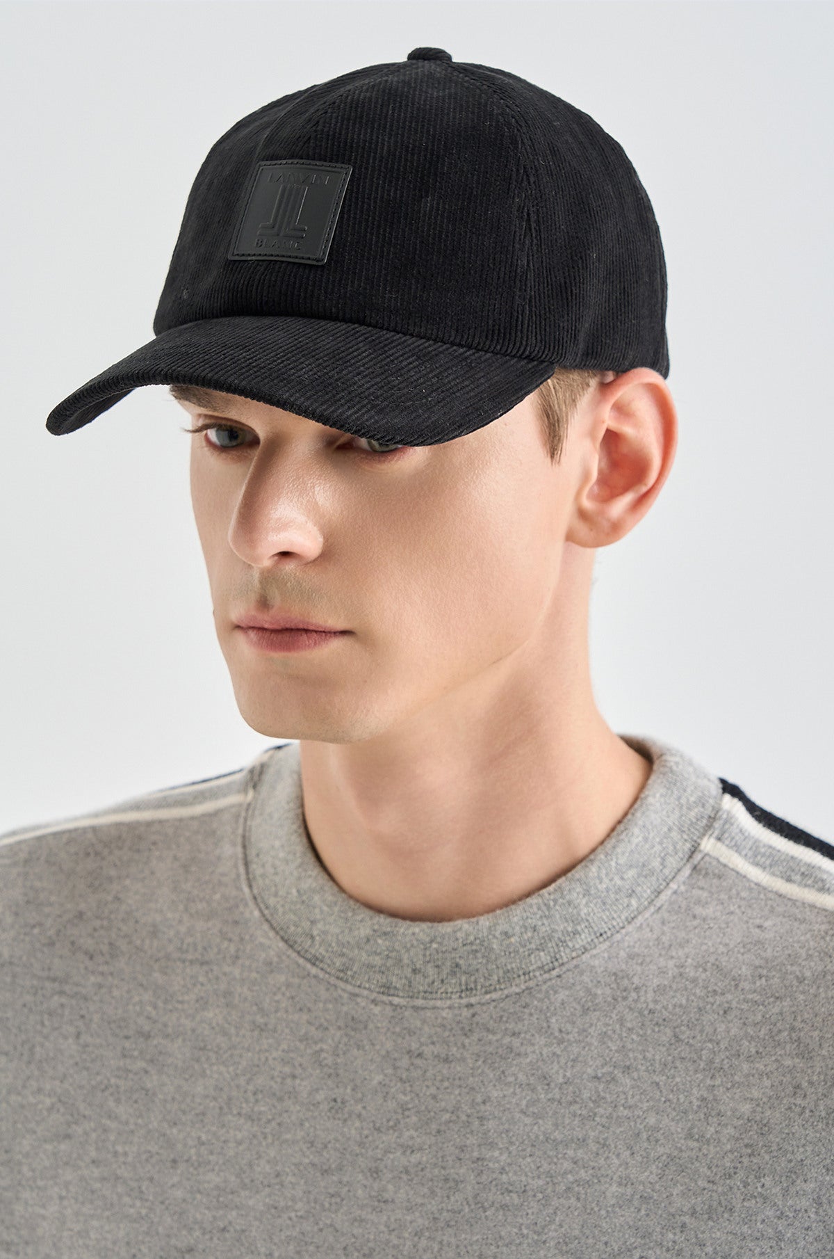 Man wearing a black cap with a small patch on a light gray background