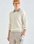 Person wearing a beige sweater, brown cap, and golf glove on a light gray background