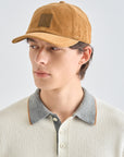 Person wearing a brown cap and light-colored sweater with a gray collar against a white background