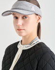 Person wearing a gray visor and black quilted jacket with visible branding on a light gray background