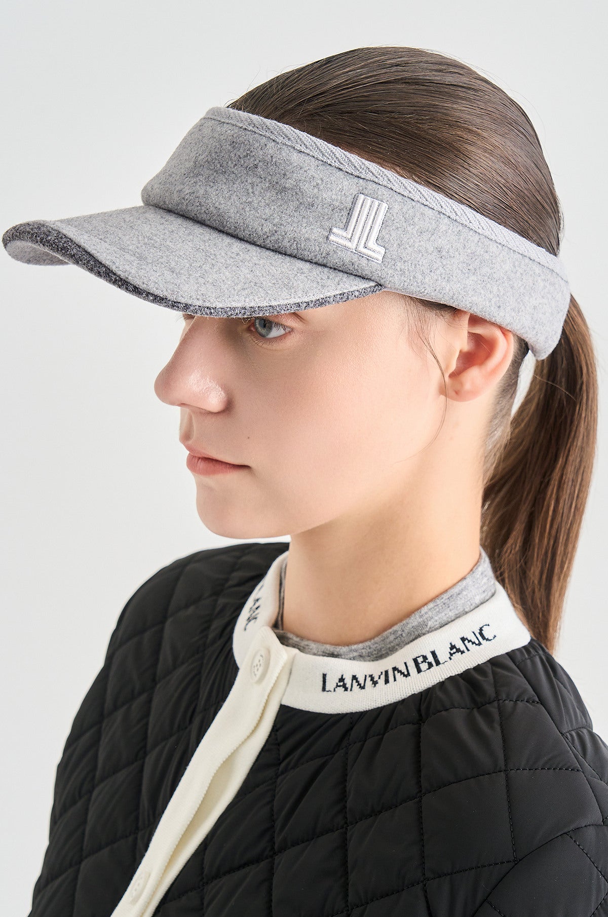 Person wearing a gray visor with a brand logo on a white background
