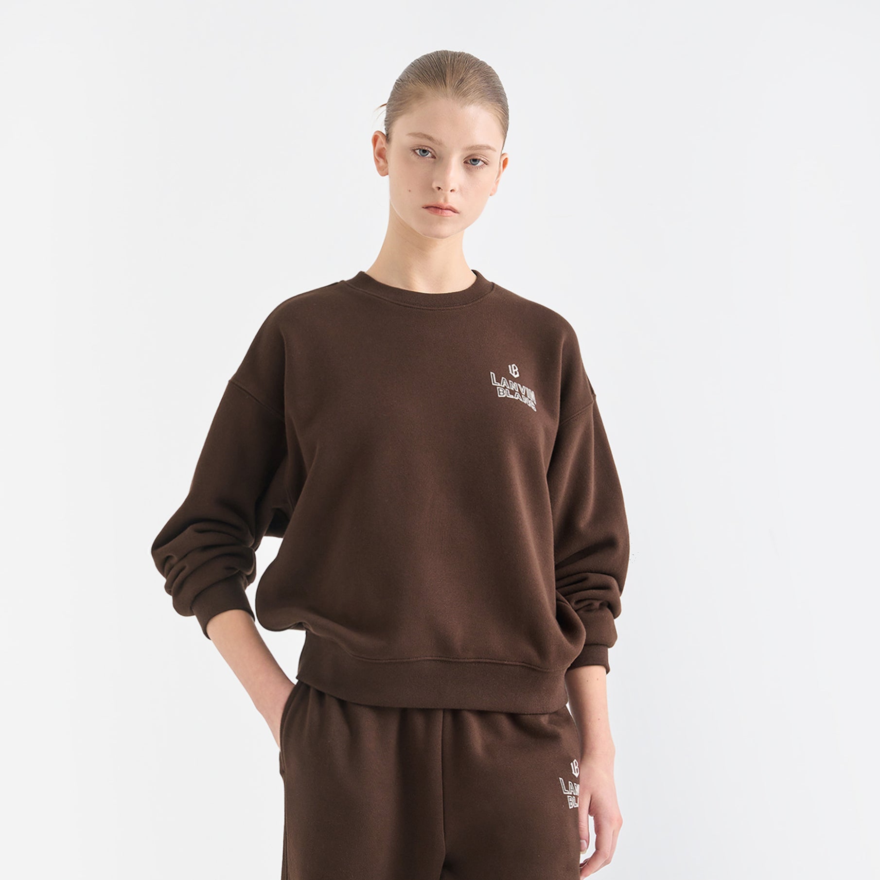 Person wearing a brown sweatshirt and pants set with a logo on a white background
