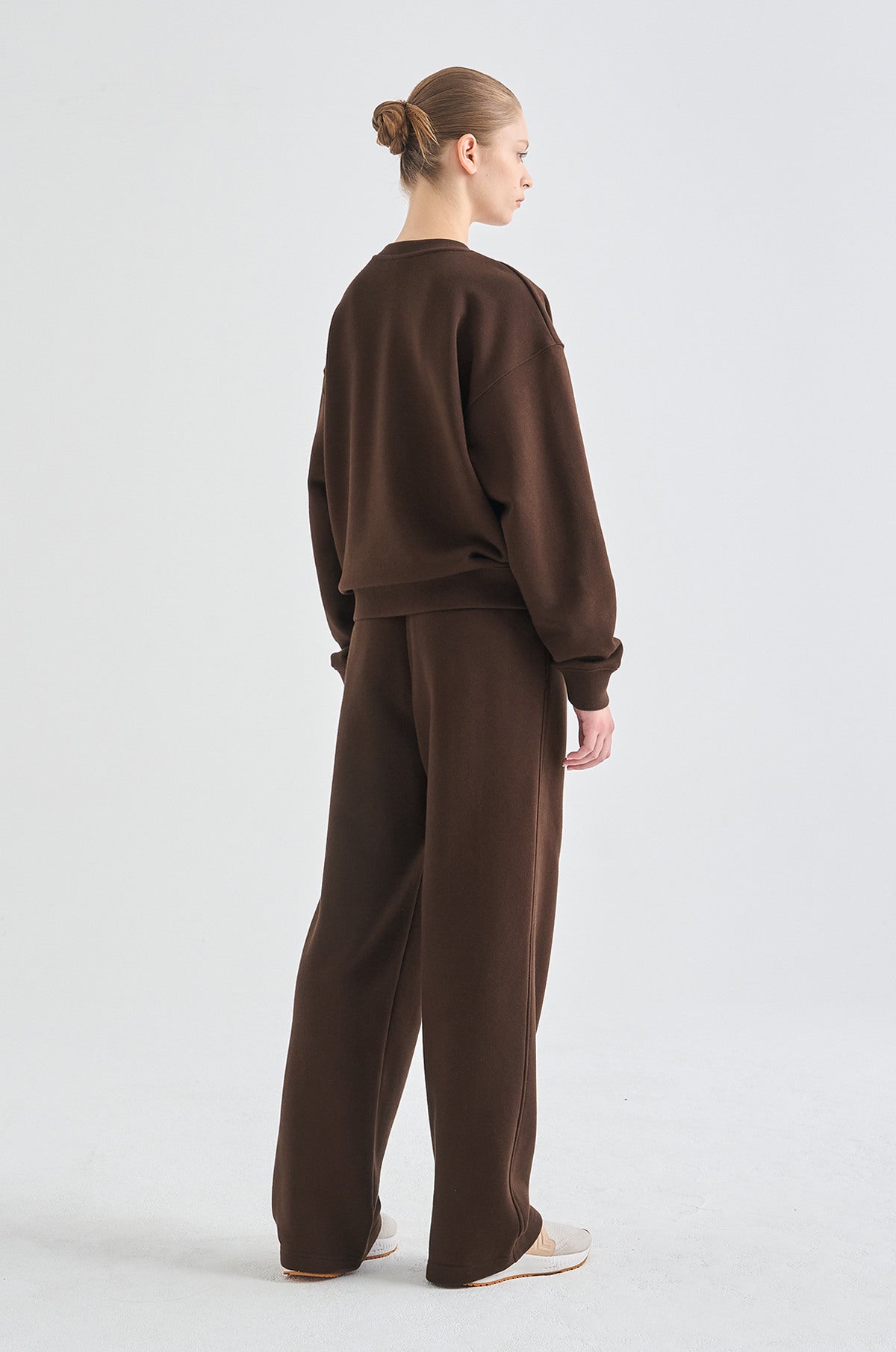 Person wearing a brown tracksuit on a white background