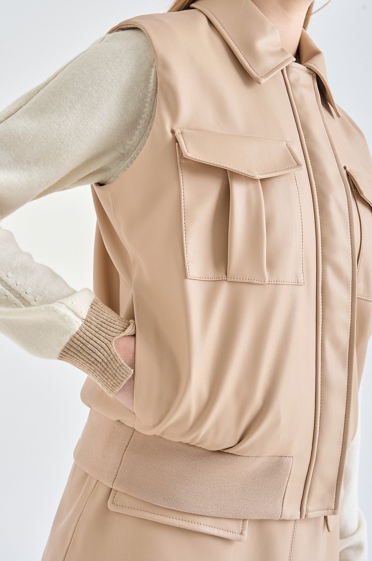 Beige vest worn over a beige jacket on a white background