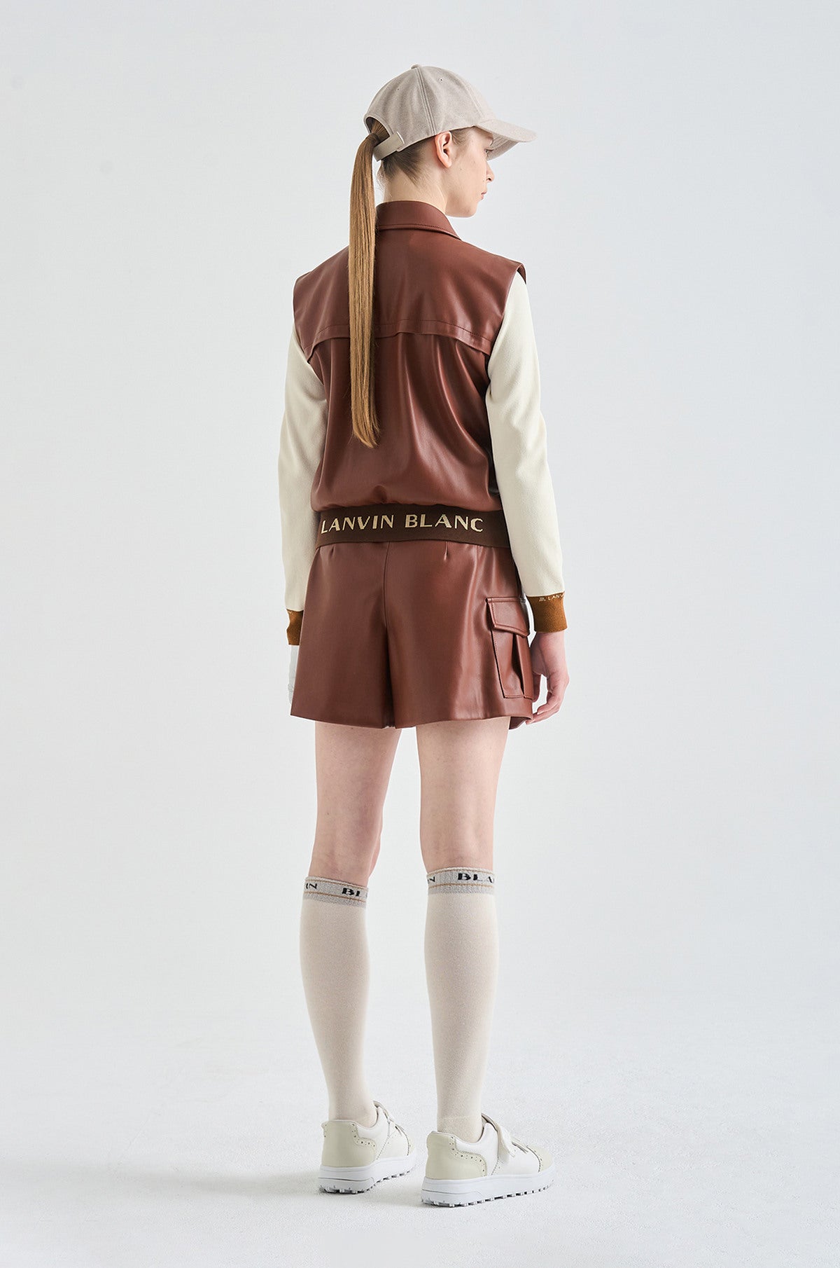 Person wearing a brown vest with 'Lanvin Blanc' branding on a white background
