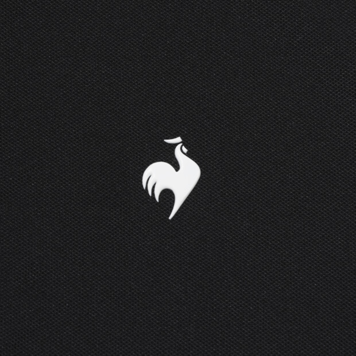 A close-up of a black textured fabric featuring the white embroidered logo of the French Rooster, representing the brand Gauloises.