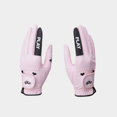 A pair of light pink golf gloves with black accents, featuring the brand name 'PLAY' on the back of the hands and 'GOLF' on the wrist strap, displayed against a light gray background.