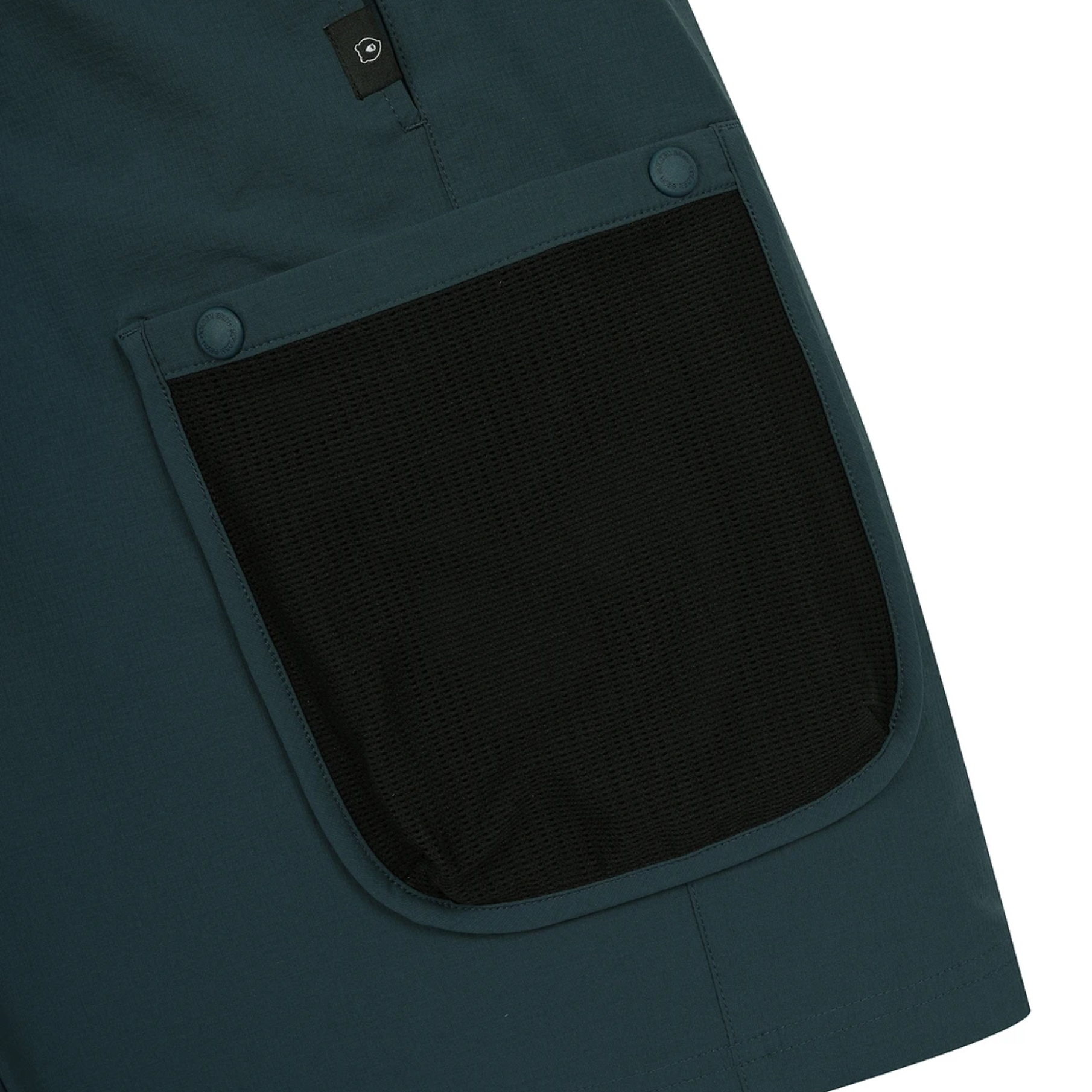 Close-up of a dark teal utility pocket with a black mesh insert and snap-button closure on a white background.