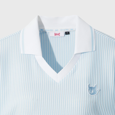 Close-up of women's light blue seersucker golf polo with white collar, V-neck, and embroidered chest logo.