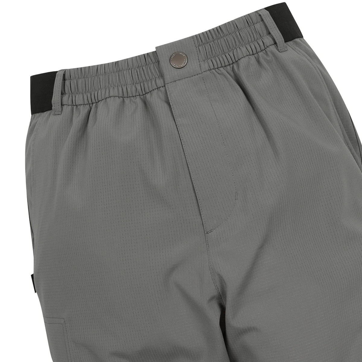 Close-up of gray athletic pants showing the elastic waistband with a black side tab, a metal snap button, and the side pocket.
