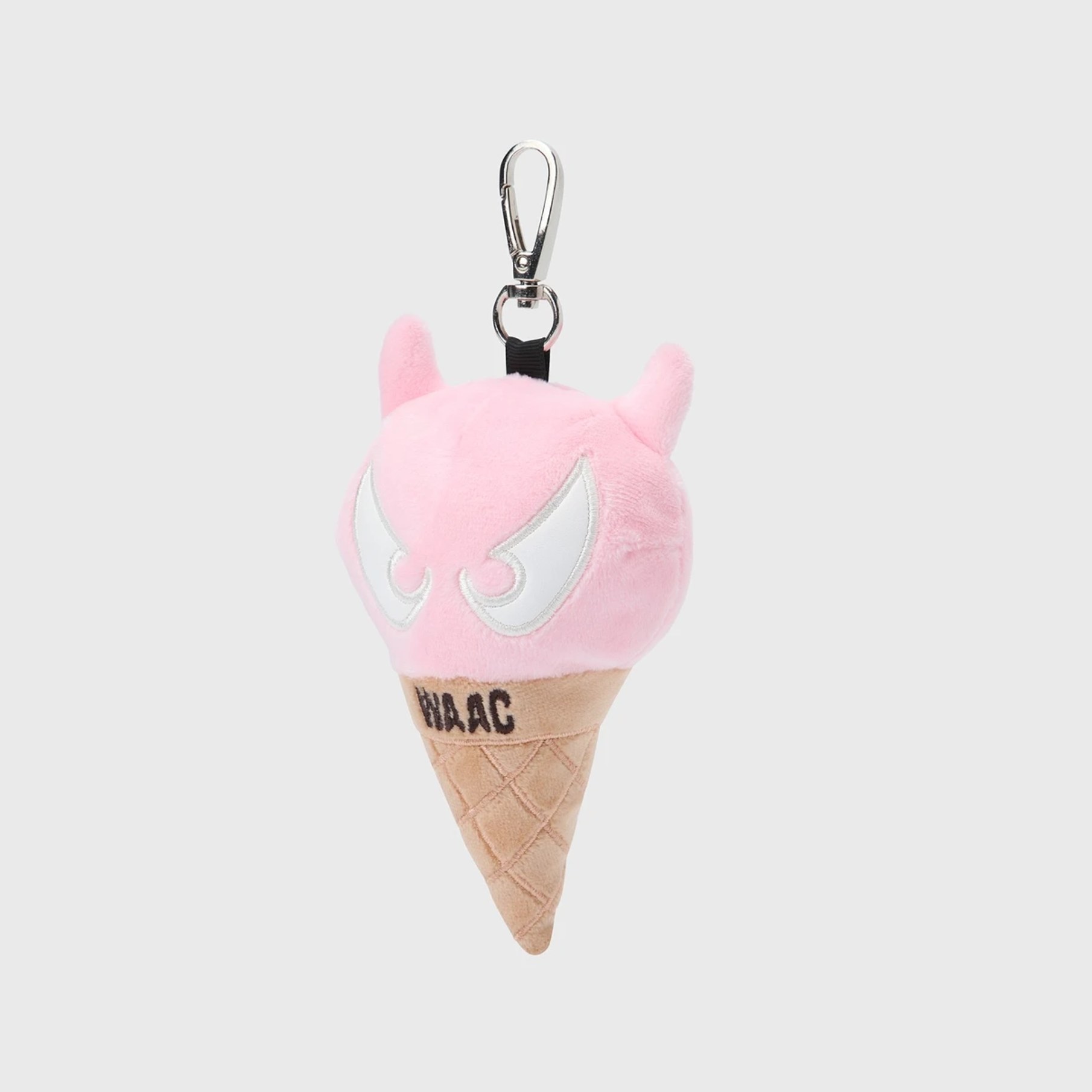 A pink plush ice cream cone keychain with embroidered eyes, small horn-like ears, and a silver metal clasp on a light gray background.