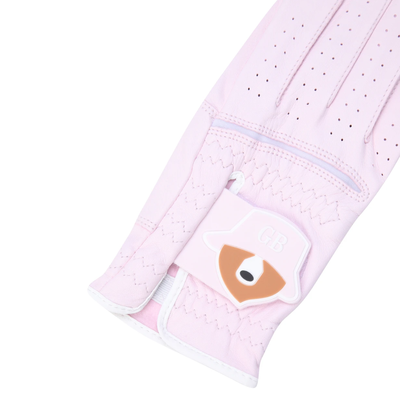A close-up of a light pink golf glove with a decorative patch featuring a raccoon face and the letters 'GB' on the back of the hand, set against a plain white background.