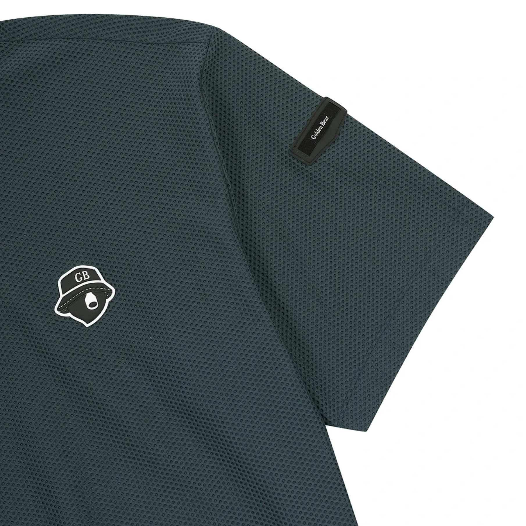 Close-up of a dark green textured short-sleeve shirt with a white embroidered chest logo and a black sleeve tag reading 'GB'.