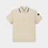 A light beige short-sleeve polo shirt with a black-trimmed collar and a small white embroidered shield logo on the left chest, displayed on a clean light gray background.