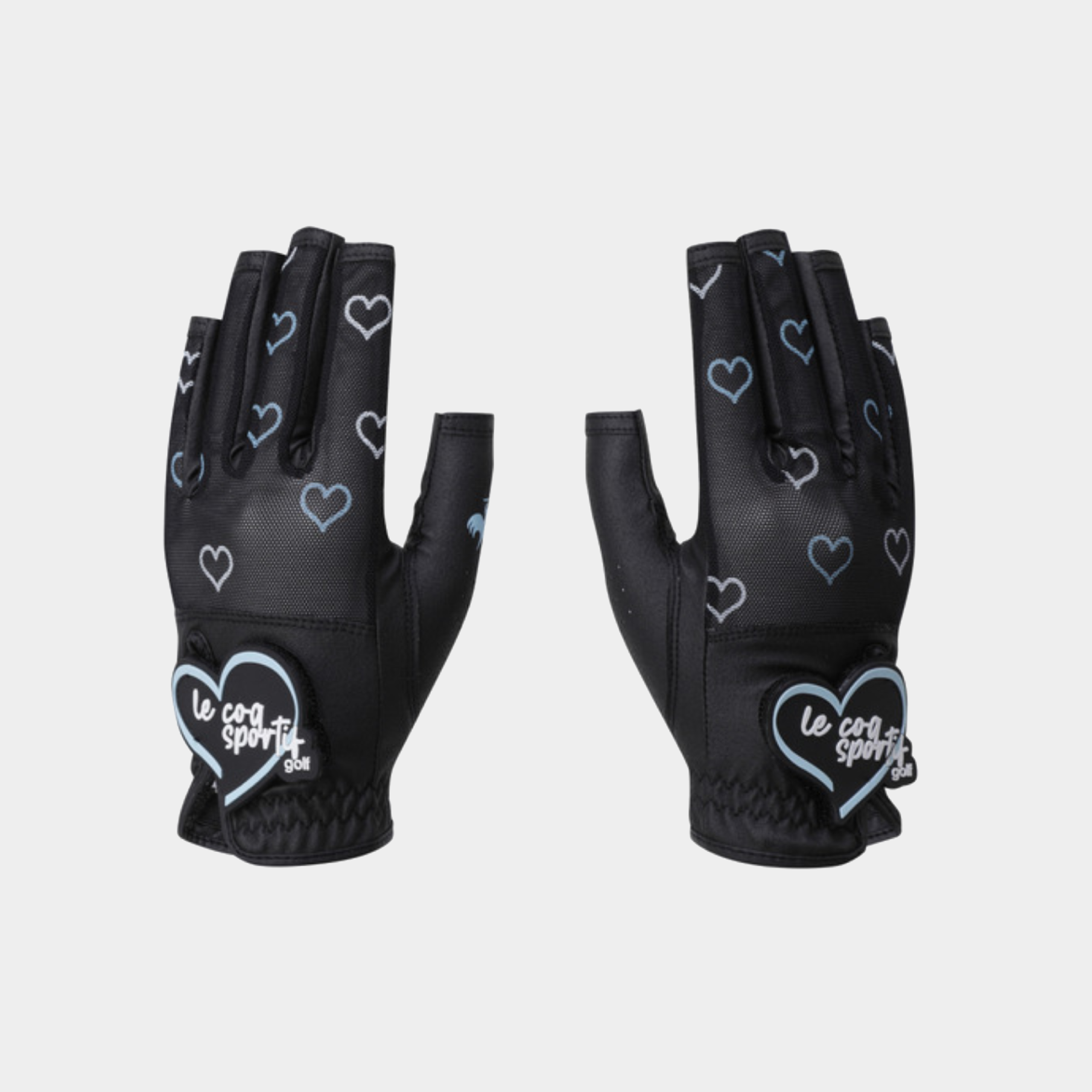 A pair of black fingerless cycling gloves with a pattern of light blue outlined hearts and a white heart patch on the back of the hand that reads 'le coq sportif'.