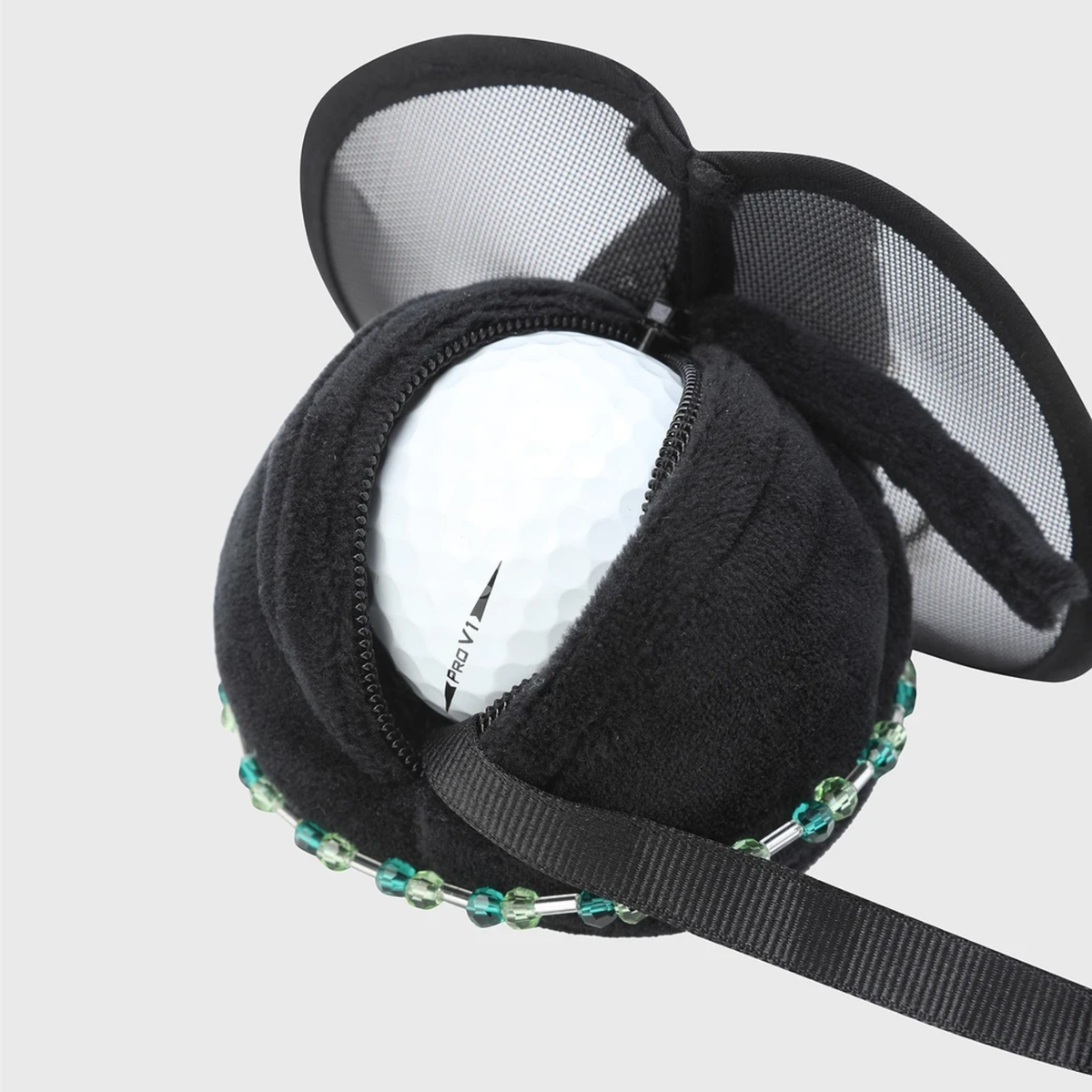 A black plush golf ball holder with mesh wings and a beaded trim, shown holding a white golf ball on a light gray background.