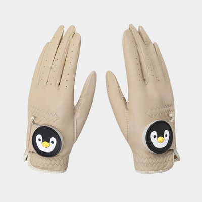 A pair of beige leather golf gloves with a circular penguin patch on the back of the hand, shown against a light gray background.