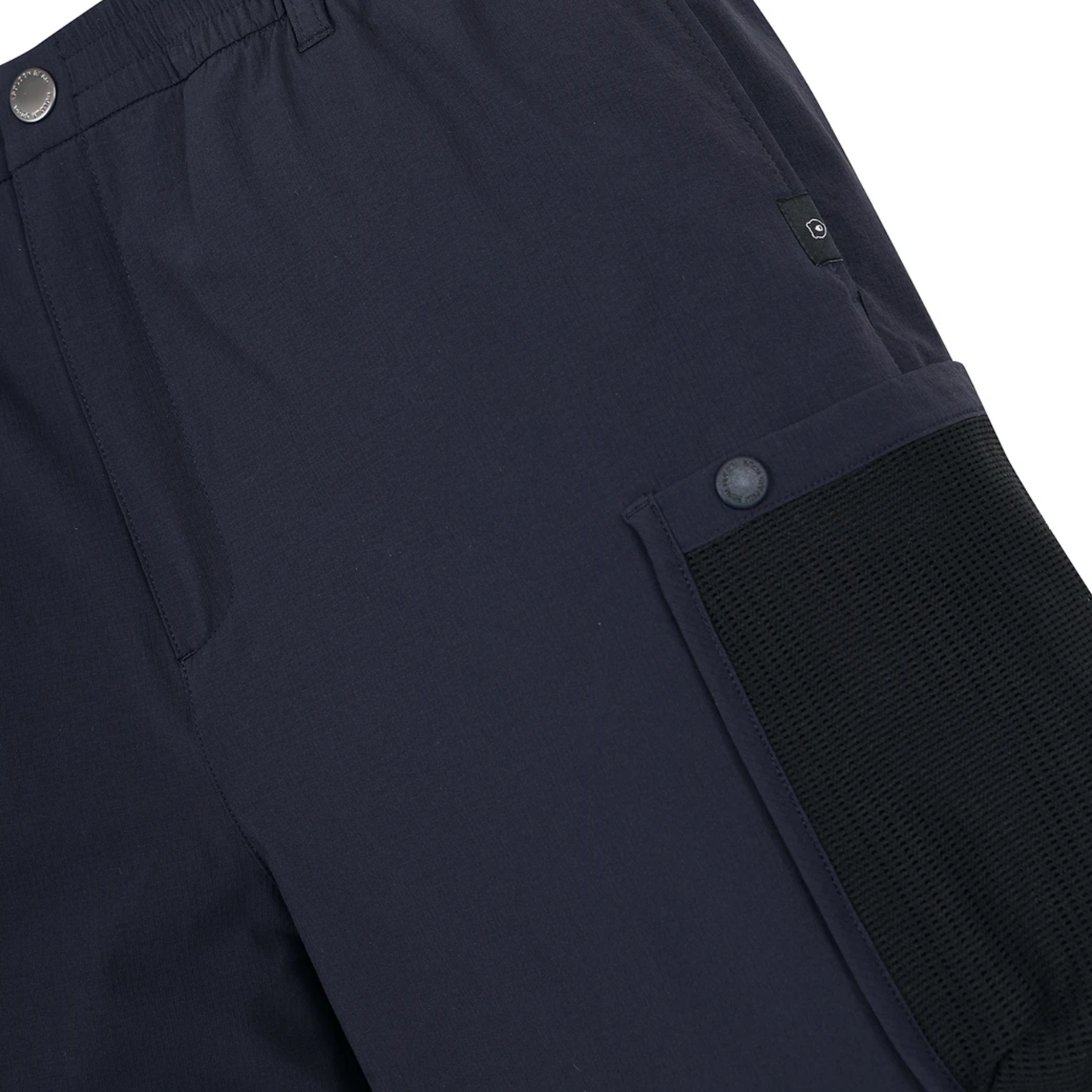 Close-up of dark navy pants showing a side pocket with a black mesh panel and a snap button, along with part of the waistband and metal snap details.