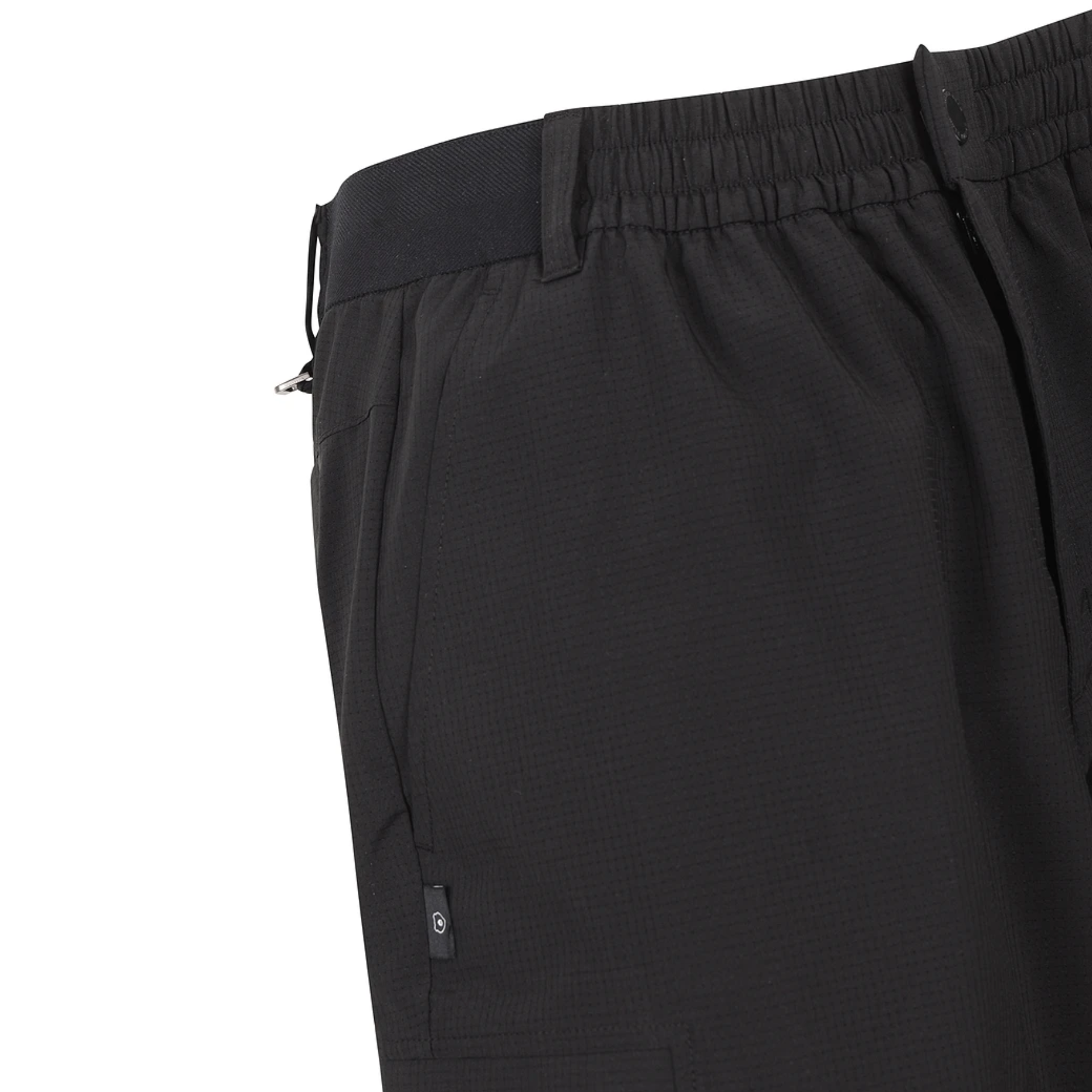 Close-up of black athletic shorts showing the elastic waistband, side pocket, and a small circular logo tab near the hem, set against a plain white background.